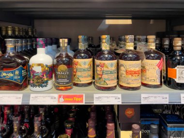 Almanya 11 Mayıs 2024. Rafta bir sıra içki şişesi, bir şişe Bakire Meryem de dahil. Şişeler sıraya dizildi, bazıları diğerlerinden daha uzun.