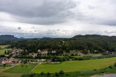 Trenin geçtiği kırsal bir bölge. Gökyüzü bulutlu ve kasaba küçük. Tren kargo taşıyor.