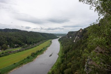 Üzerinde tekne olan bir nehir ve arkasında bulutlu bir gökyüzü.