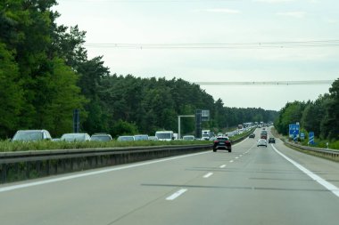 Almanya, 17 Mayıs 2024. Üzerinde bir sürü araba ve kamyon olan yoğun bir otoyol. Arabalar yavaş ilerliyor ve yol boyunca birkaç trafik ışığı var..