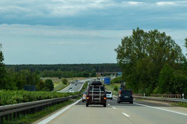 Almanya, 17 Mayıs 2024. Yolun ortasında kırmızı bir araba olan işlek bir otoyol. Araba büyük bir bagaj rafı taşıyor..