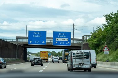 Almanya 17 Mayıs 2024. Üzerinde Goritz Baautzen yazan mavi tabelası olan işlek bir otoyol. Yolda bir sürü araba var, bir kamyonet ve kamyonet de dahil..
