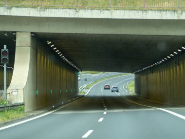 Ortasında tünel olan bir otoyol. Tünel karanlık ve arabalar oradan geçiyor.
