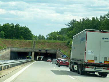 17 Mayıs 2024 'te bir kamyon arka planda bir tünel olan bir otoyol boyunca ilerliyor. Tünel karanlık ve tek görünen araç kamyon değil..