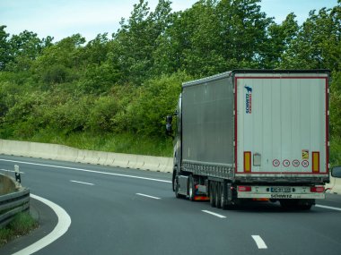 Almanya 17 Mayıs 2024 Büyük bir kamyon yeşil bir ormanın arka planına doğru ilerliyor. Kamyon büyük bir römork taşıyor ve otoyolda.