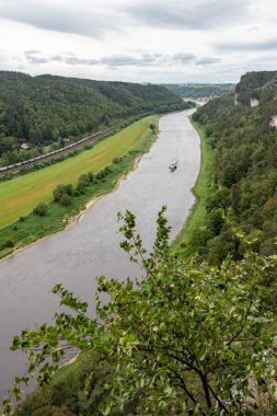 Üzerinde tekne olan bir nehir. Su sakin ve gökyüzü bulutlu. Huzurlu ve huzurlu bir sahne.