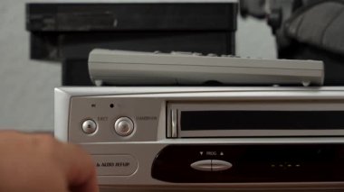 Üzerinde uzaktan kumanda olan gümüş ve siyah bir video oynatıcı. Gümüş ve siyah VCR.