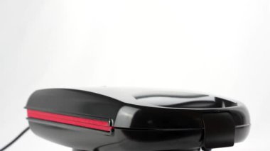 Arkasında kırmızı ışık olan siyah bir tost makinesi.