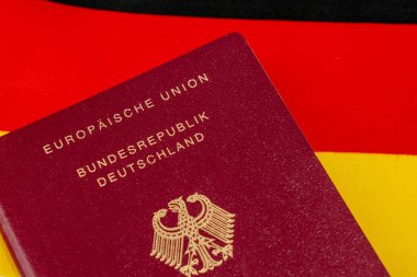 Bir Alman vatandaşının kırmızı pasaportu. Pasaport Alman bayrağının tepesine konur..