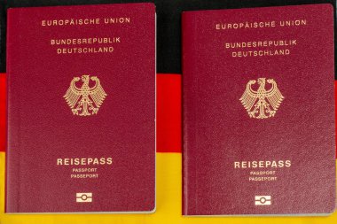 Bir Alman vatandaşının iki kırmızı pasaportu. Alman bayrağının arka planına karşı pasaport.