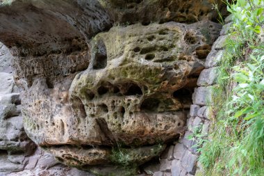 İçinde delikler olan bir kaya oluşumu. Delikler küçük ve sayısız. Kaya kahverengi ve gri.