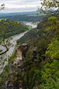 Arka planda dağ olan güzel bir nehir manzarası. Ağaçlar yemyeşil, su da sakin. Sahne huzurlu ve huzurlu. Rahatlamak ve doğanın tadını çıkarmak için harika bir yer.