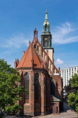 Saat kulesi ve yeşil çatısı olan büyük bir kilise. Bina ağaçlarla çevrili ve çok eski ve tarihi bir görünüme sahip.