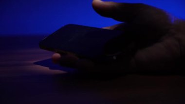 Akıllı telefonlu bir el, yanıp sönen polis ışıklarının arka planına karşı masaya düşer. Akıllı telefonlu yakın plan el..