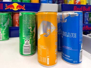 Almanya 12 Ağustos 2024. Bir mağazada bir sıra Red Bull konservesi sergileniyor. Kutular yeşil, sarı ve mavi olmak üzere farklı renklerde.