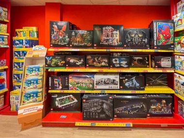 Almanya 12 Ağustos 2024. Raflarda bir sürü lego olan bir mağaza. Raflar kırmızı ve sarı. Bir ejderha, bir ev ve bir tren de dahil olmak üzere birçok farklı lego çeşidi vardır.