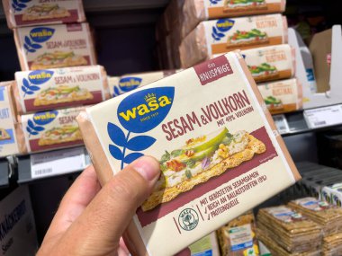 Almanya 12 Ağustos 2024. Elinde bir kutu Wasa krakeri tutan bir adam. Krakerler diğer krakerlerle birlikte bir rafta sergileniyor..