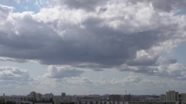 Şehrin üzerindeki bulutların zamanlaması. Mavi gökyüzündeki beyaz bulutlar şehrin üzerinde süzülüyor.