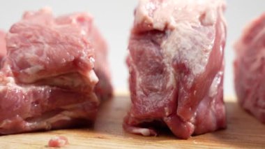 Tahta kesme tahtasındaki domuz eti beyaz arka planda döner. Beyaz üzerine çiğ domuz eti..