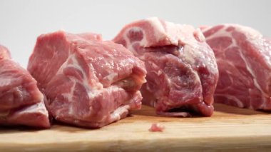 Kesme tahtasındaki domuz eti beyaz arka planda döner. Beyaz üzerine çiğ domuz eti..