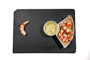 A plate of food with white sauce and surimi in the form of shrimp. On a plate of food there is a shrimp tail. Surimi in the form of shrimp on a white background. clipart