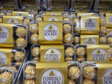Almanya 4 Eylül 2024. Bir rafta altın renkli Ferrero Rocher çikolatası yığını var. Şekerler şeffaf plastik bir kapta..