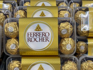 Almanya 4 Eylül 2024. Bir yığın altın renkli Ferrero Rocher çikolatası. Çikolatalar şeffaf plastik bir kapta.