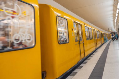 Almanya 15 Eylül 2024. Üzerinde bisiklet etiketi olan sarı bir metro treni. Tren hareket halinde ve bir platformla çevrili.