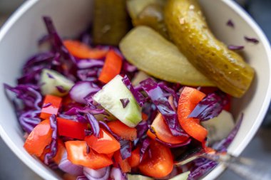 Salatalık ve turşu dahil çeşitli sebzelerle bir kase salata. Salata renkli ve iştah açıcı.
