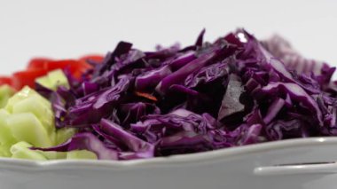 Salatalık ve domates de dahil olmak üzere çeşitli sebzeli beyaz tabak. Salata beyaz arkaplanda döner.