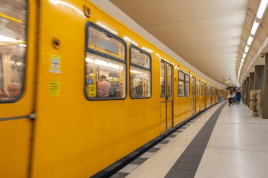 Almanya 15 Eylül 2024. İstasyonda sarı bir metro treni duruyor ve insanlar binmek için bekliyor. İnsanlar Berlin 'i gezmeye hazırlanırken sahne hareketli ve hareketli..