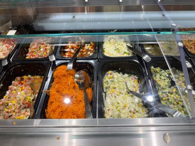 Farklı salata ve sebzelerle dolu bir salata barı. Salata barı havuç, brokoli ve marul da dahil olmak üzere farklı türde salata ve sebzelerle dolu.