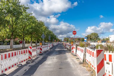 Kırmızı ve beyaz çizgili çitli bir yol ve kırmızı ve beyaz bir tabela. Yol boş, içinde ne araba ne de insan var. Yolda tamir işleri..