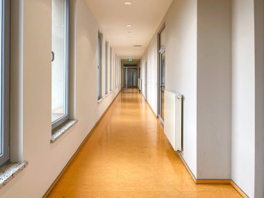 Duvarında radyatör olan uzun bir koridor. Koridor boş ve duvarlar beyaz.