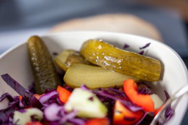 Bir kase turşu ve lahana. Turşular kasenin ortasında ve lahana sol tarafta.