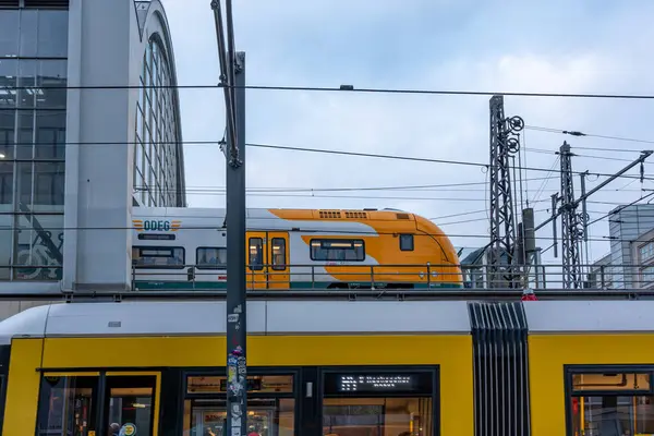 Almanya 16 Kasım 2024. Raylarda sarı beyaz bir tren var. Tren hareket ediyor ve etrafı kablolarla çevrili.