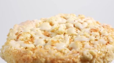 Beyaz kremalı kurabiyelerin yakın çekimi. Yuvarlak şekilli kurabiyeler beyaz bir zemin üzerinde döner ve biraz ufalanan bir dokuya sahiptir. Jöle tabağa parlak bir bakış verir ve biraz tatlılık katar..