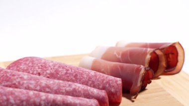 Ahşap kesme tahtası, jambon ve salam da dahil olmak üzere çeşitli etlerle döner. Jambon ince şeritler halinde kesilir ve salam daha küçük parçalara ayrılır..