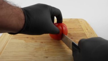 Domates kesme tahtasıyla parçalara ayrılır. Beyaz arkaplanda tahta ve domates kesme.