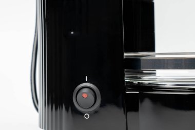 Yanında kırmızı düğmesi olan sade bir kahve makinesi. Düğme 