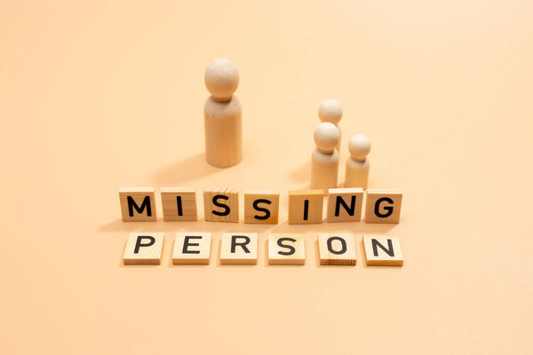 Группа людей, сделанная из деревянных фигур. Группа стоит перед табличкой с надписью "Пропавший без вести". Концепция поиска себя или пропавших без вести.