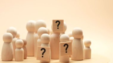 Bir grup ahşap insan soru işareti taşıyor. İnsanlar kim oldukları sorusuna bir cevap bulmaya çalışırken merak ve belirsizlik kavramı.