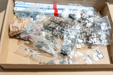 Mobilya montaj setiyle birlikte karton kutu. Vidalar, ahşap perdeler, kapı menteşeleri, cıvatalar, mobilya montajı için yedek parçalar.