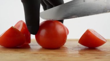 Domates kesme tahtasıyla parçalara ayrılır. Beyaz arkaplanda tahta ve domates kesme.