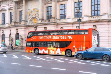 Almanya Berlin, 26 Aralık 2024. Yan tarafında Top Tour turu yazan kırmızı çift katlı bir otobüs. Otobüs, arkasında bir araba olan bir caddede park halinde.