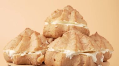 Üstünde beyaz dolgu olan üç pasta. Pişmiş mallar üst üste istiflenir. Pasta turuncu arka planda döner..