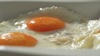İki yumurta beyaz bir tabakta döner. Yumurtalar portakal beyazı..