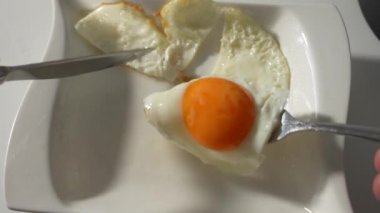 Bir insan çatal ve bıçağı yumurtanın üzerinde tutuyor. Yumurta ikiye bölünmüş ve çatal yumurtadan çıkmış.