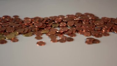 Gri yüzeyde bir yığın bozuk para. Yığında bir sürü bozuk para var. Bozukluklar gri bir masanın üzerinde duruyor. Kamera masanın üzerinde duran bozuk para yığını boyunca hareket eder..