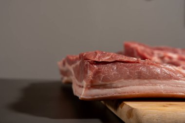 Tahta kesme tahtasının üzerinde bir parça et var. Et parçalara ayrılmış.